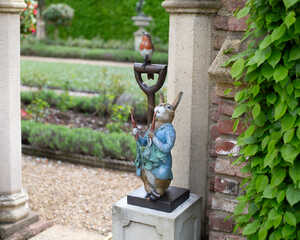 A garden sculpture of Peter Rabbit Eating Radishes with a Robin and Dibber