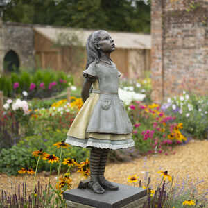 Bronze statue of Alice, surrounded by colorful flowers at Forde Abbey