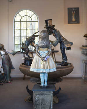 Alice in Wonderland sculpture standing in front of a Tea Party Urn at Robert James Workshop gallery