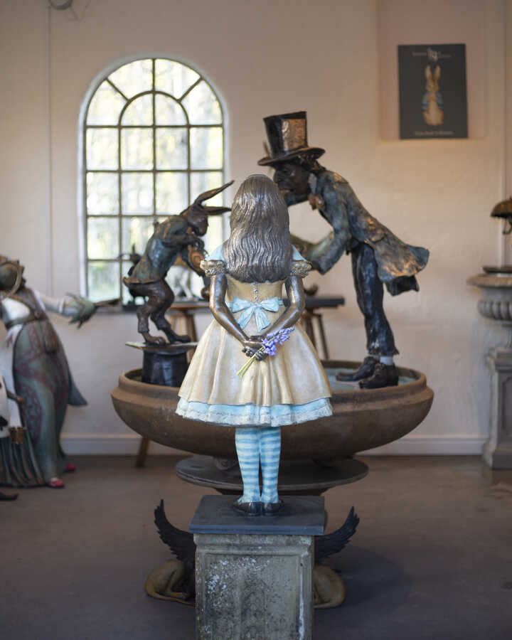 Alice in Wonderland sculpture standing in front of a Tea Party Urn at Robert James Workshop gallery