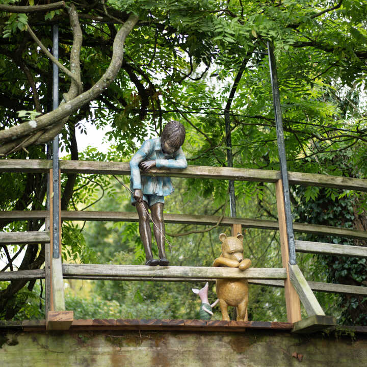 Winnie the Pooh, Piglet, and Christopher Robin, look over the Poohsticks Bridge - A garden sculpture from Robert James Workshop