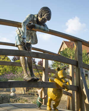 christopher robin playing poohsticks on a birdge with winnie the pooh
