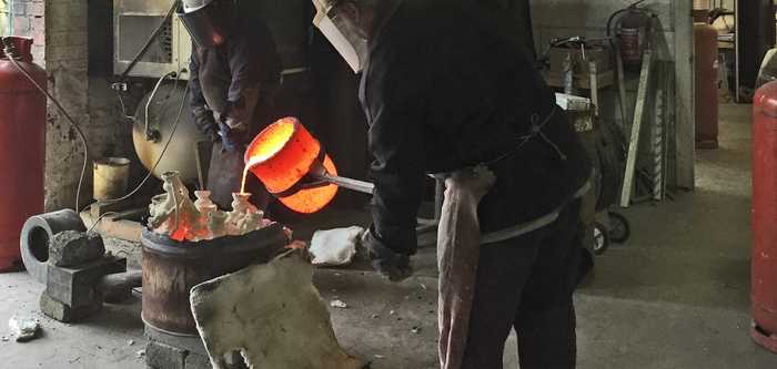 pouring molten bronze into cast