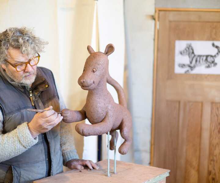James modelling Tigger in clay, with E.H. Shepard’s illustration behind him